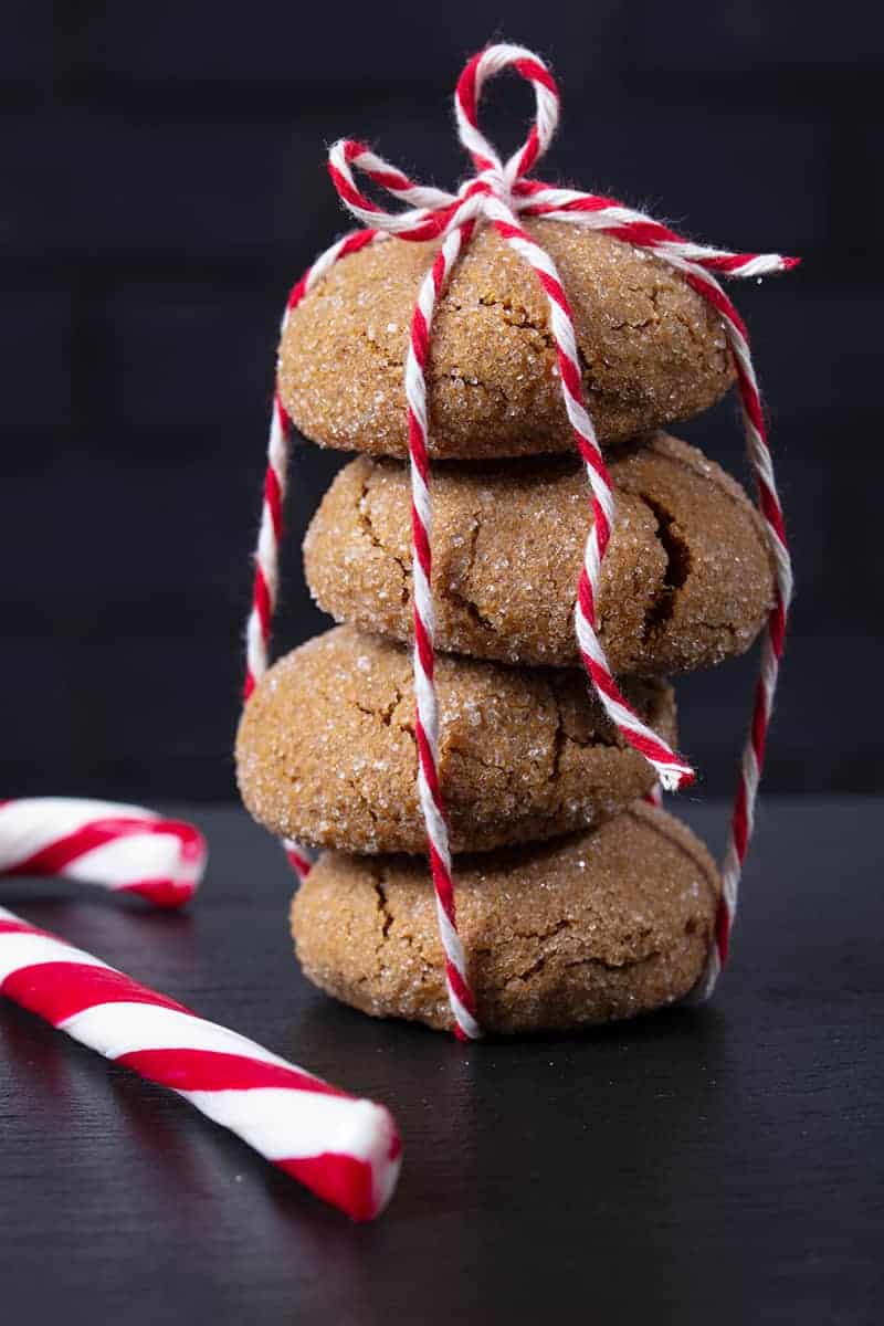 close up stack of Molasses Cookies tied with red and white ribbon, Christmas candy bar on side