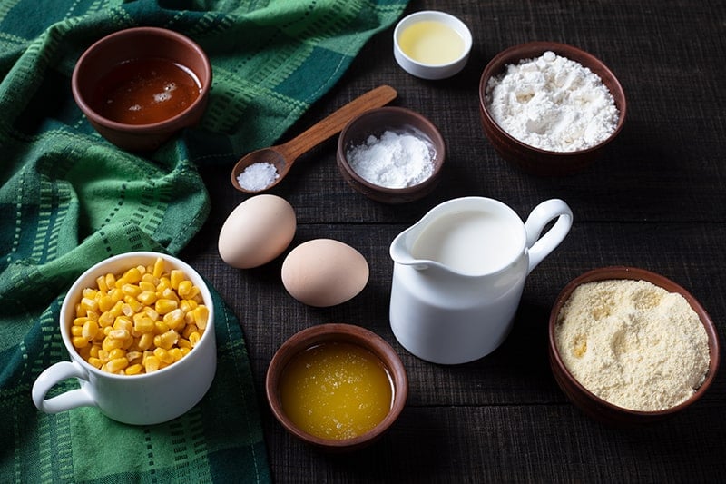 Ingredients are mise on place for making cornbread on a table with green tablecloth 