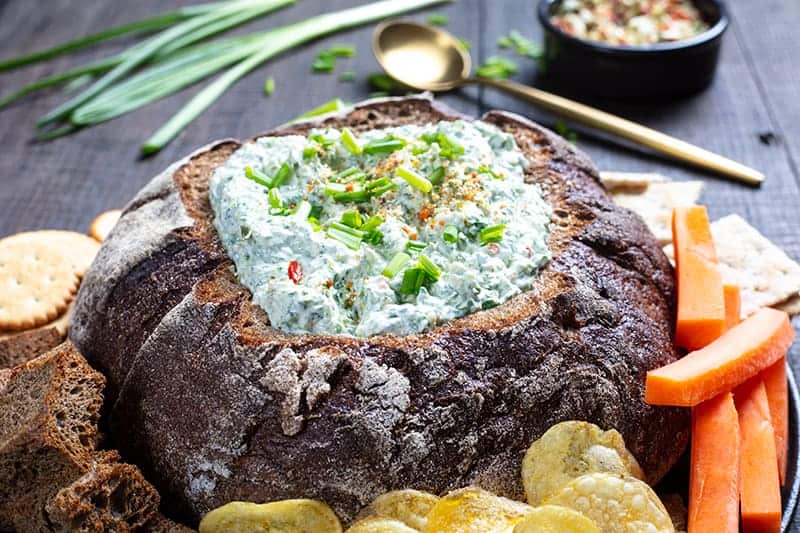 Knorr Spinach Dip in a bread bowl with some crisp crackers, potato chips, homemade pita chips and veggies