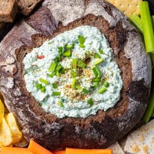 close up Knorr Spinach Dip in a bread bowl with some crisp crackers, potato chips, homemade pita chips and veggies