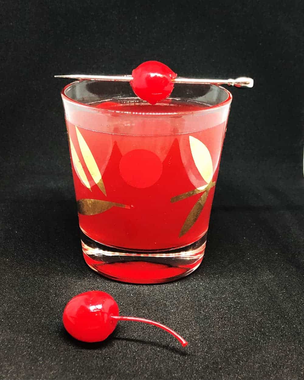 Scofflaw Cocktail on a vintage cocktail glass garnish with a stemmed maraschino cherry