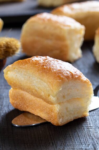 close up piece of soft buttery delicious Parker House Rolls on a wooden background