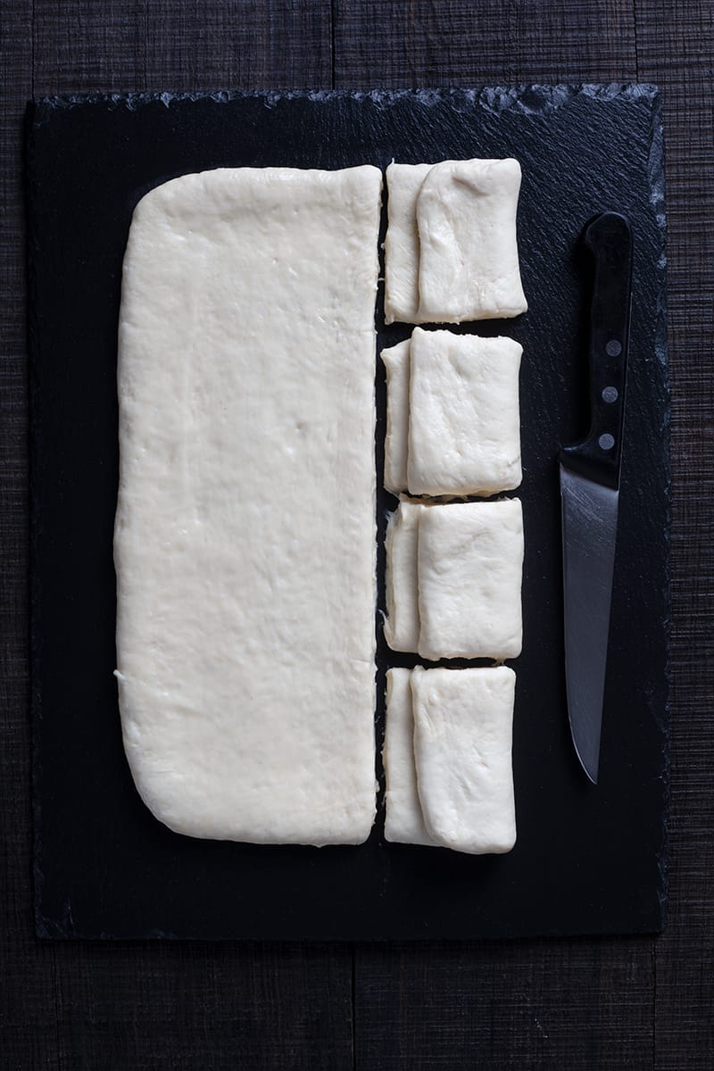 folded and sliced dough for Parker House rolls, small knife beside it