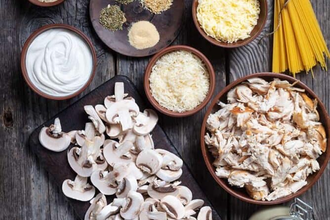 Ingredients are mise on place for making chicken tetrazzini on a wood background