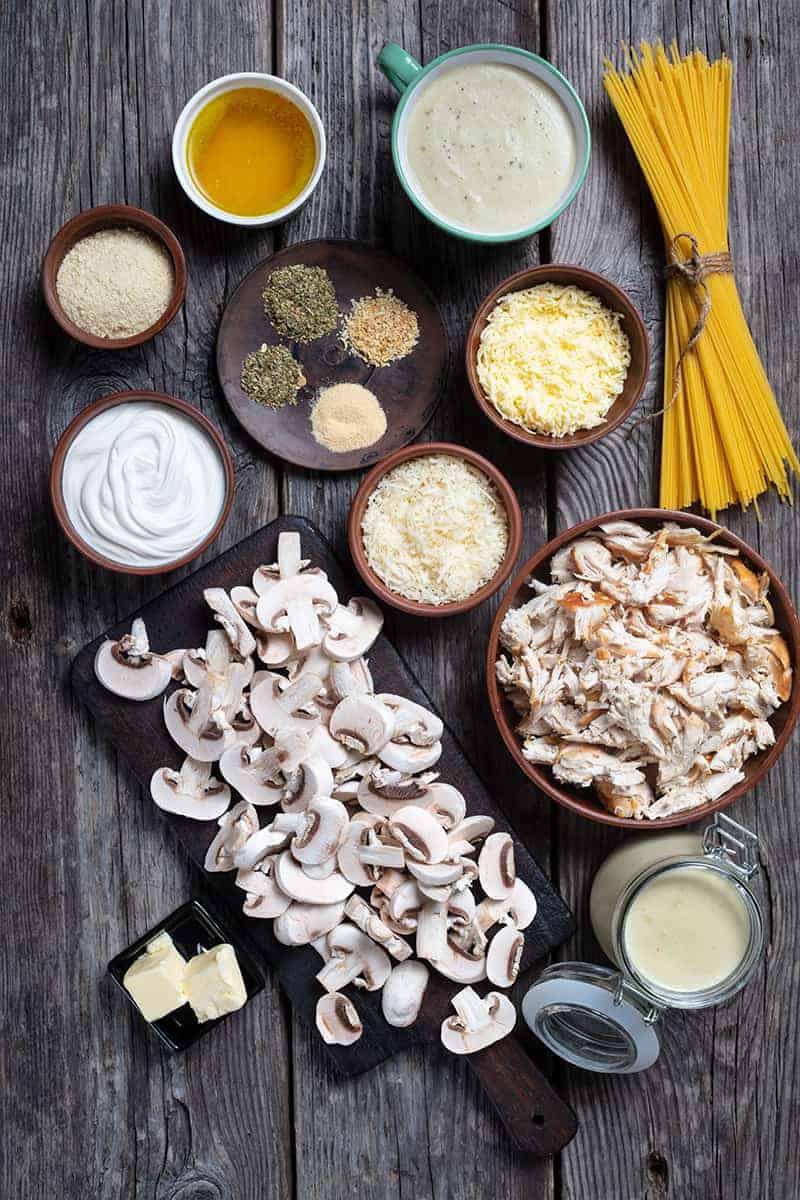 Ingredients are mise on place for making chicken tetrazzini on a wood background