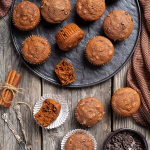 double chocolate pumpkin muffins, cinnamon sticks and chocolate chips on wooden background with polka dot brown tablecloth