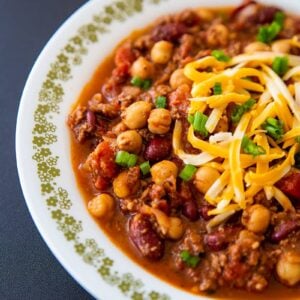 close up instant pot chili with shredded cheese on a white plate with tiny gold floral design on side