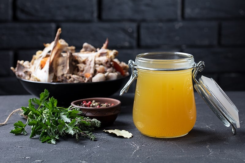 Chicken stock in an airtight glass container made with chicken bones and spices