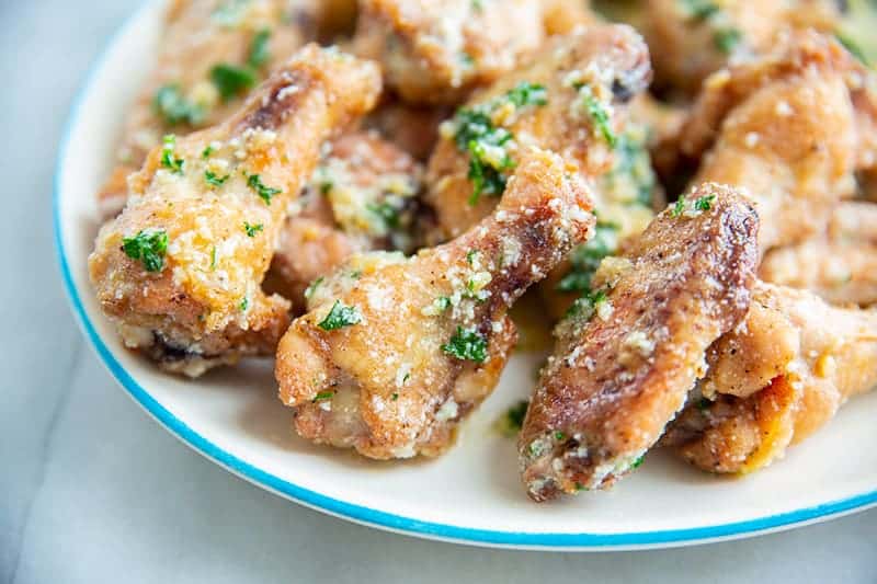 garlic parmesan chicken wings on a white plate garnished with green parsley