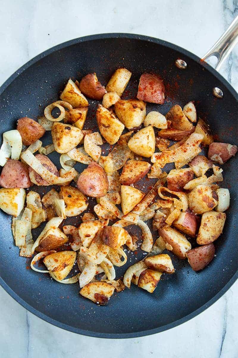 crispy pan fried potatoes and onions with paprika and black pepper in a medium sized skillet