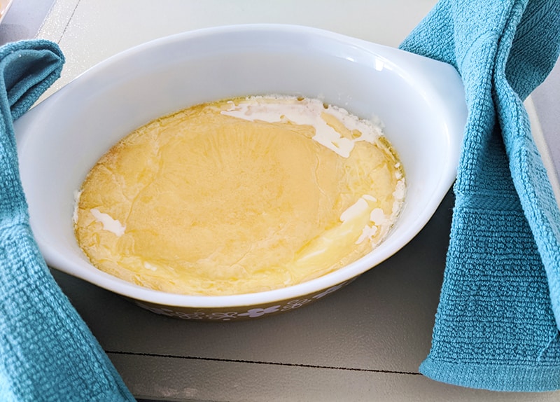 heavy cream in a casserole dish removed from oven and set aside for cooling, blue kitchen towel on each sides