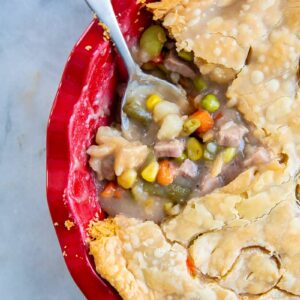 close up delicious fast & easy beef pot pie in a red pie plate, savory beef and vegetable filling encased in a two crust pot pie