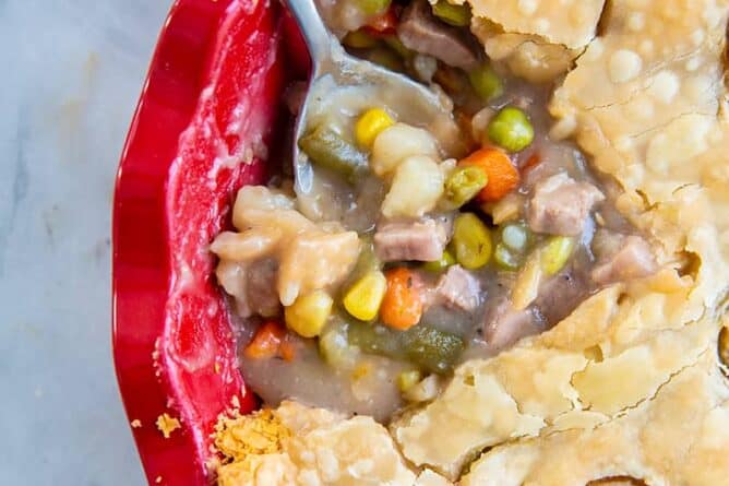 close up delicious fast & easy beef pot pie in a red pie plate, savory beef and vegetable filling encased in a two crust pot pie