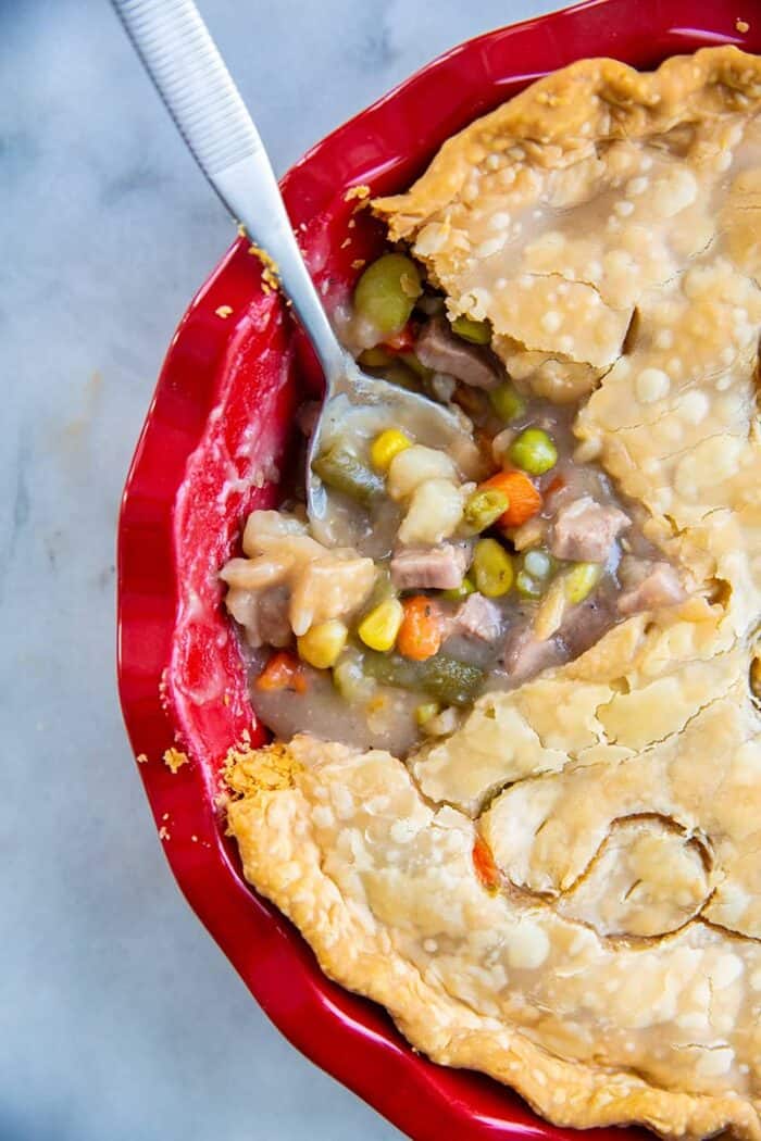 close up delicious fast & easy beef pot pie in a red pie plate, savory beef and vegetable filling encased in a two crust pot pie
