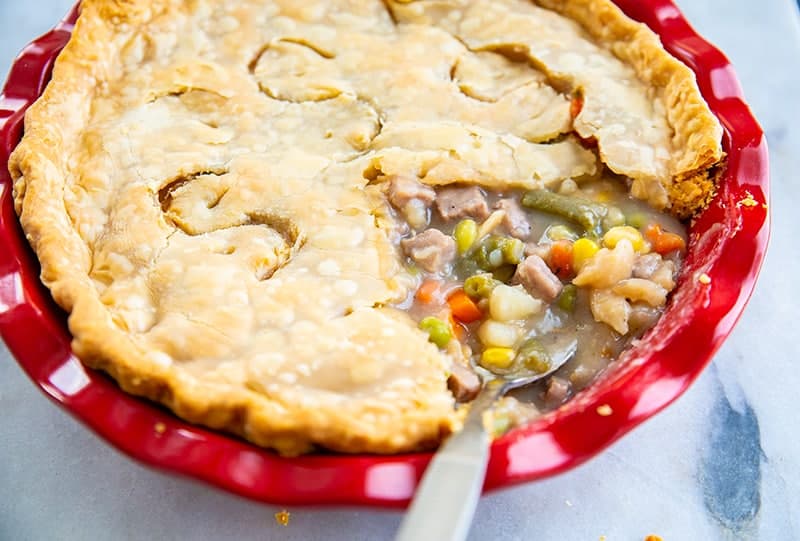delicious fast & easy beef pot pie in a red pie plate, savory beef and vegetable filling encased in a two crust pot pie