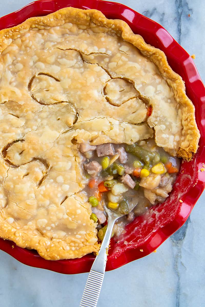 close up delicious fast & easy beef pot pie in a red pie plate, savory beef and vegetable filling encased in a two crust pot pie