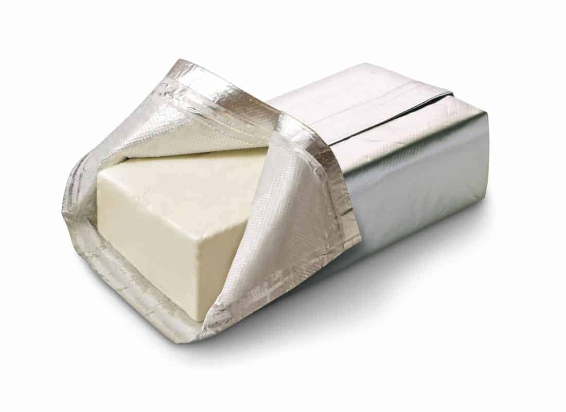 whole cream cheese wrapped in a foil wrapper with one side opened 