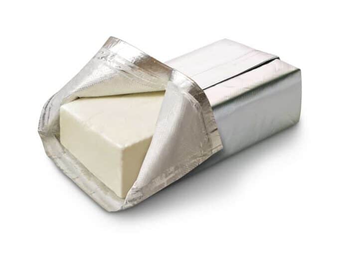 whole cream cheese wrapped in a foil wrapper with one side opened