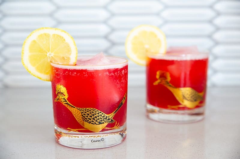 Cranberry Whiskey Sour in a vintage roadrunner decorated glasses garnished with lemon