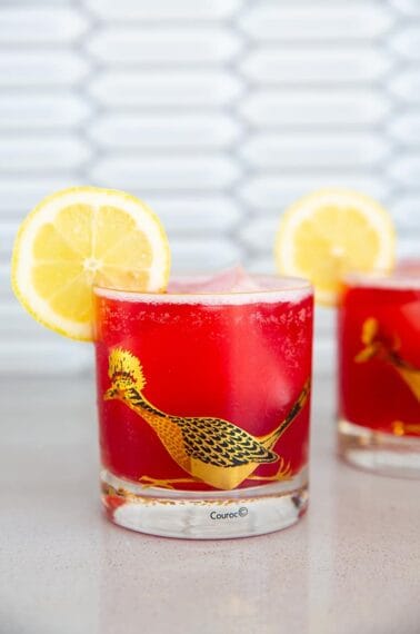 Cranberry Whiskey Sour in a vintage roadrunner decorated glass garnished with lemon