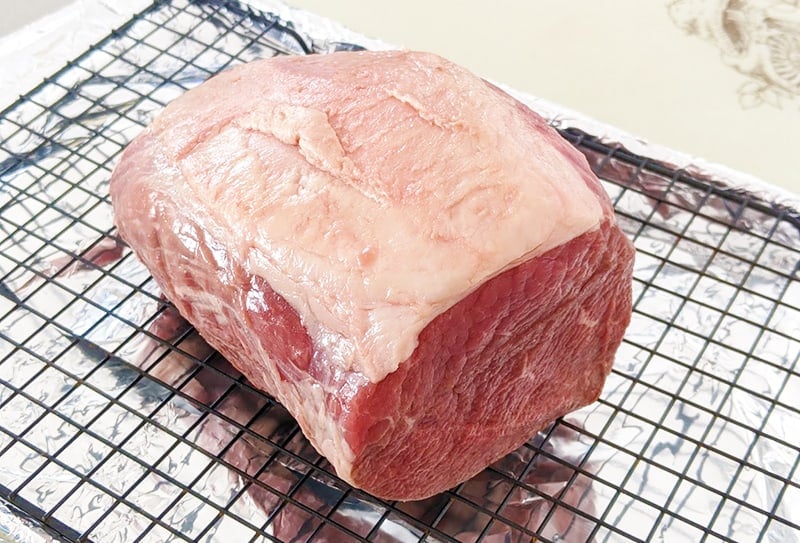 uncooked eye of round roast on a roasting rack with fat cap side up