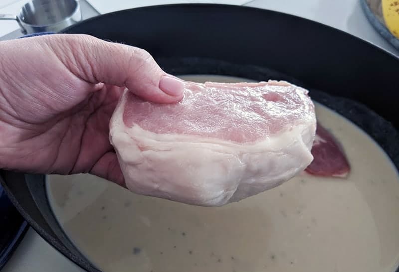 placing the frozen pork chop and gently immersing it into the soup