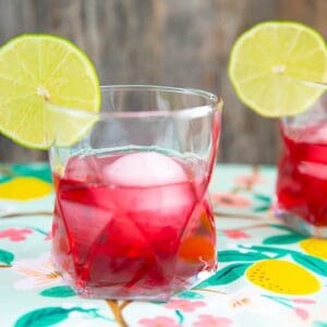 the woo woo cocktail, cranberry red drink in a clear glass garnished with lime