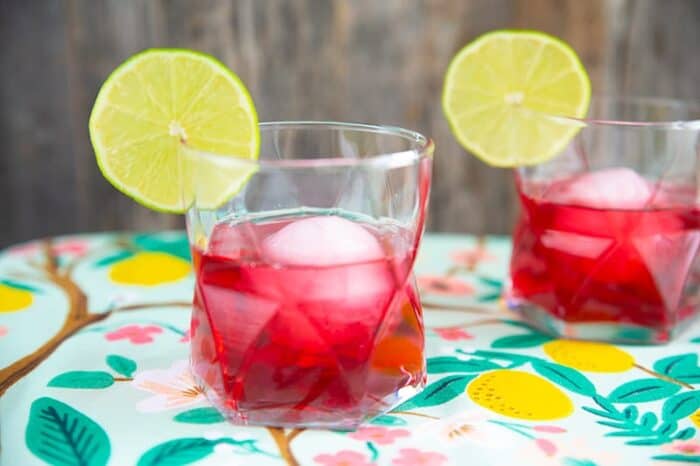 the woo woo cocktail, cranberry red drink in a clear glass garnished with lime