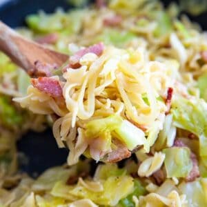 cabbage, onions and noodles with bacon on a wooden spoon