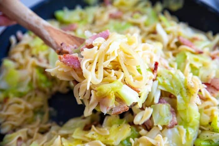 cabbage, onions and noodles with bacon on a wooden spoon
