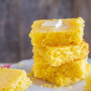 a stack of Jiffy cornbread slices with melting butter on top on a white plate