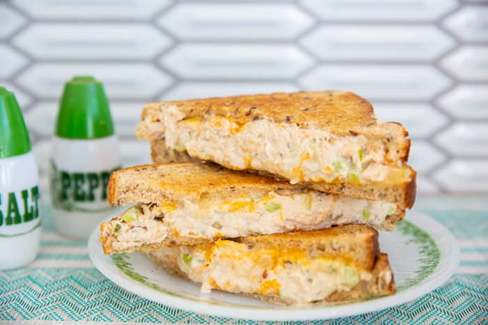 tuna melt sandwich on a white and green plate with green salt and pepper shakers