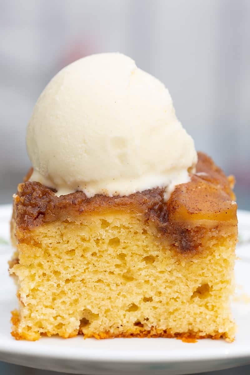 close up slice of upside down apple cake with cinnamon spice apple topping and vanilla ice cream