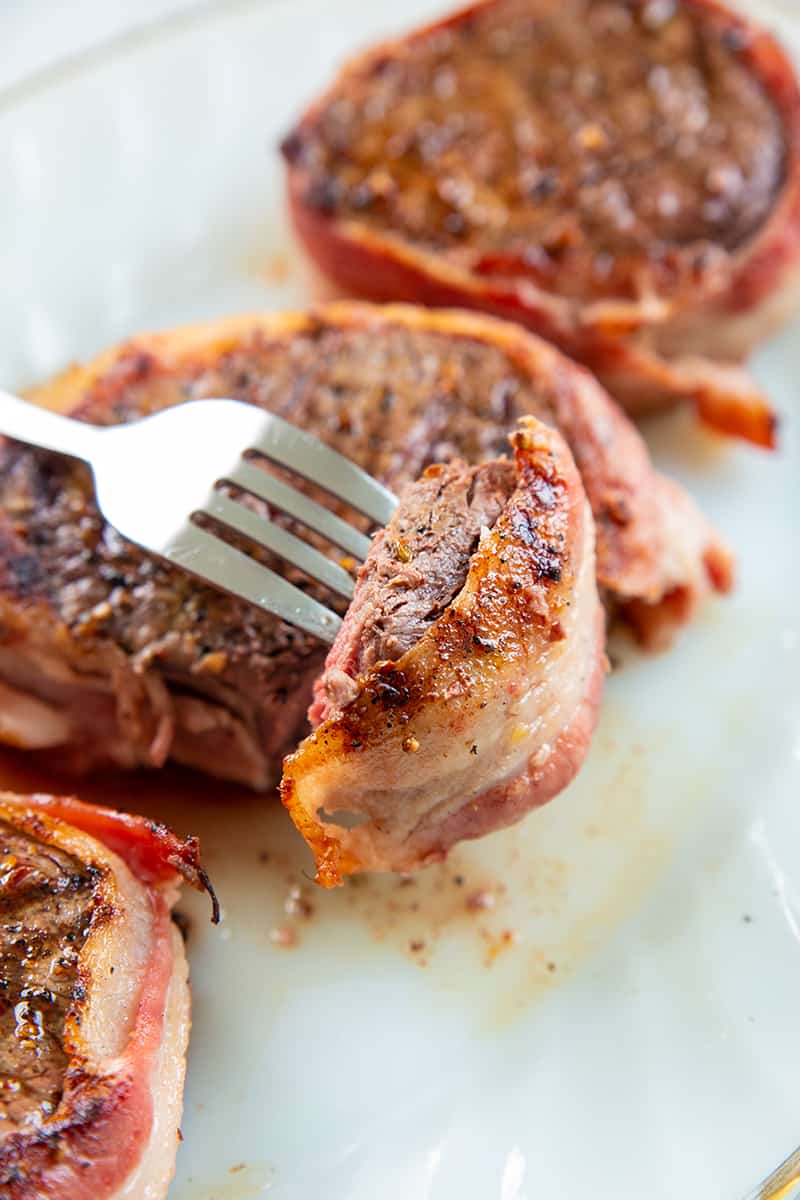 fork holding a piece of cooked filet mignon steak