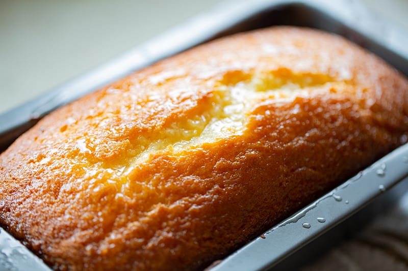 glazed lemon bread in an aluminum bread pan 