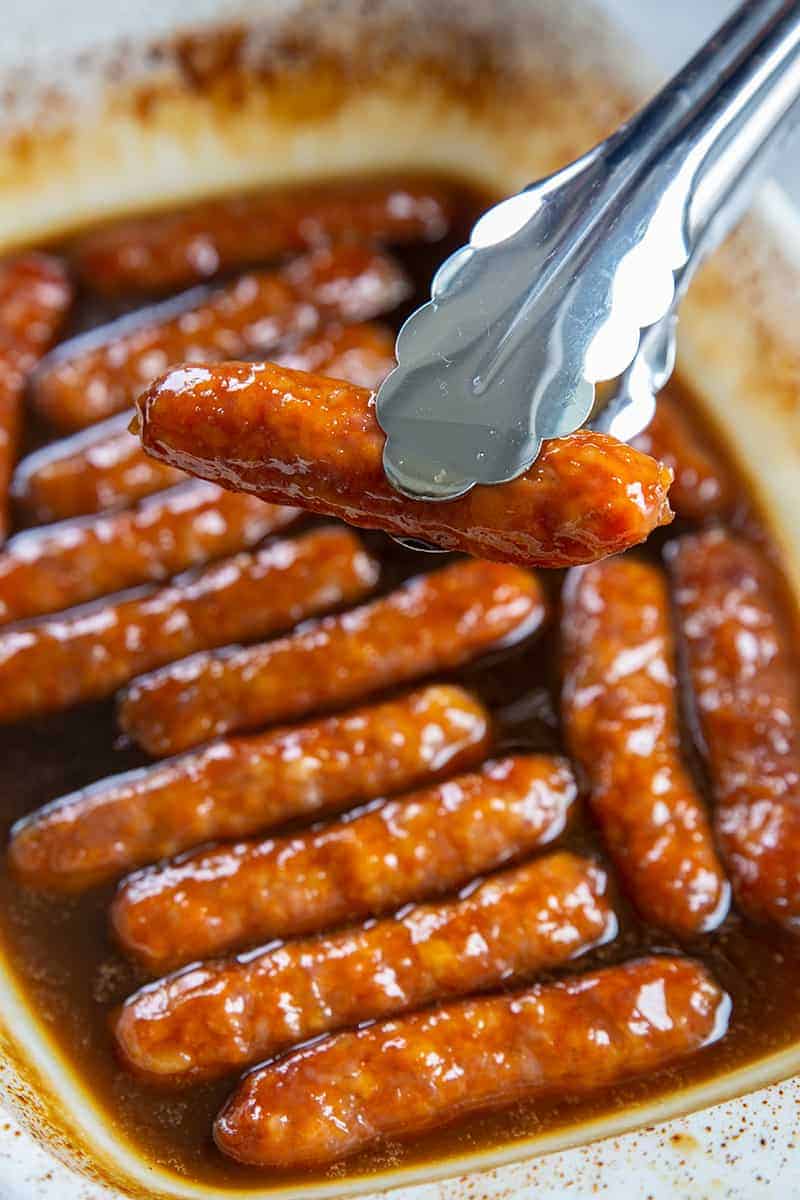 close up of a pork breakfast sausage held in metal tongs