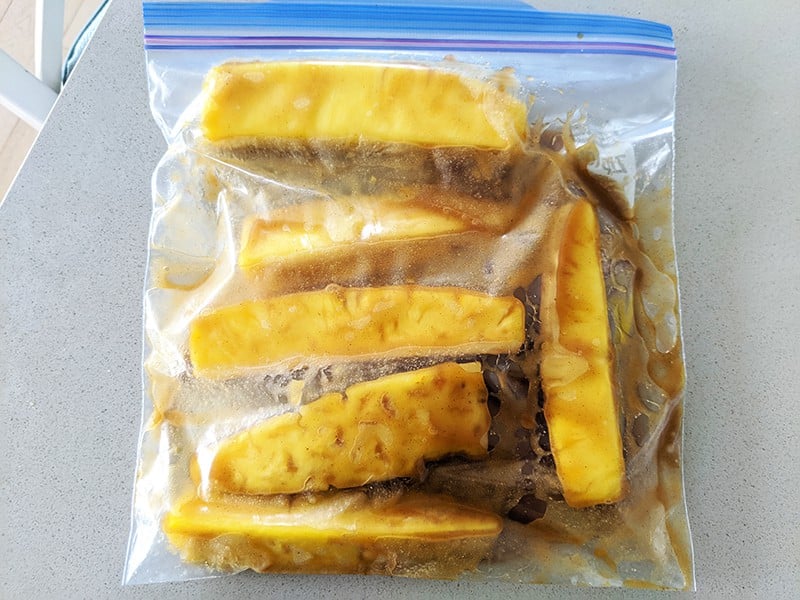 pineapple slices and marinade inside a large sealing plastic freezer bag