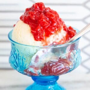 Strawberry compote on vanilla ice cream in a blue glass dish