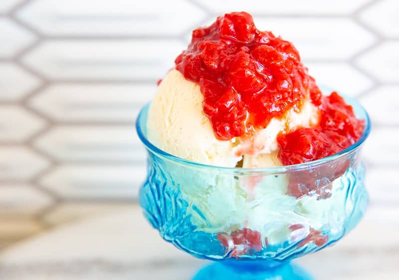 Strawberry compote on vanilla ice cream in a blue glass dish