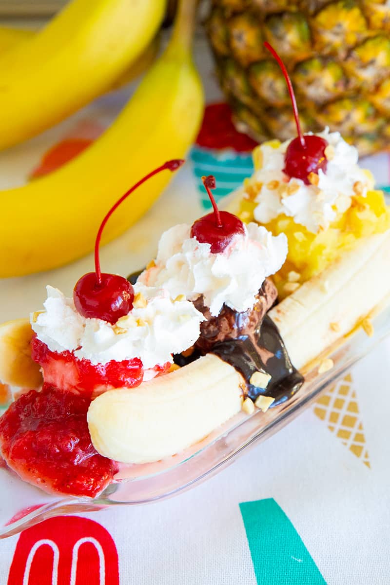 Ice Cream Banana Split on a banana boat dish, ripe banana and pineapple on background 