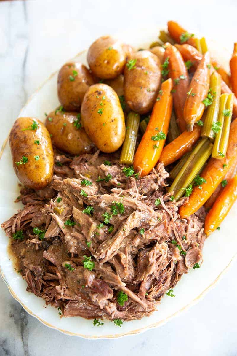 cooked pot roast on a white plate with vegetables