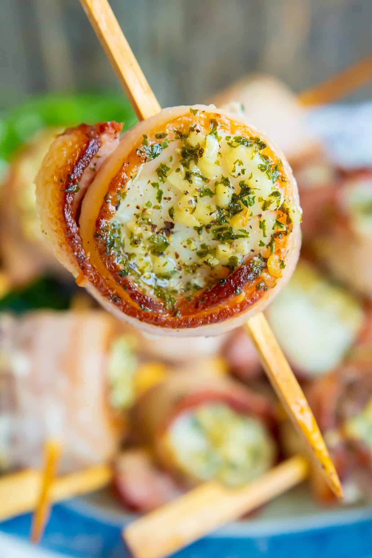 close up piece of Bacon Wrapped Scallops in a small bamboo skewer