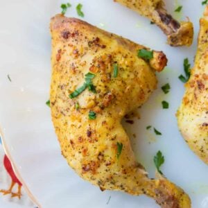 Close up Piece of Oven Baked Chicken Leg Quarters in a White Plate