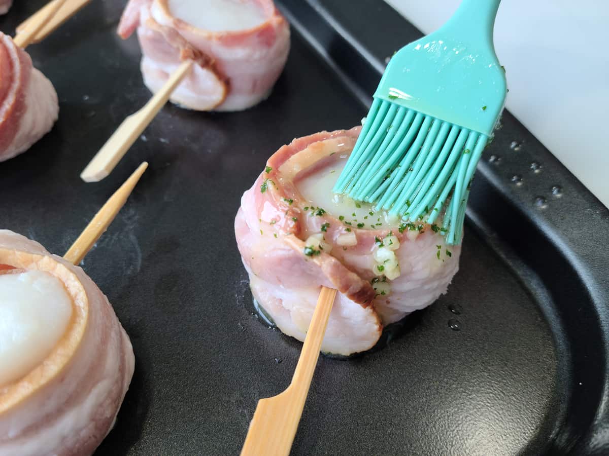 brushing the sauce on top of each scallop
