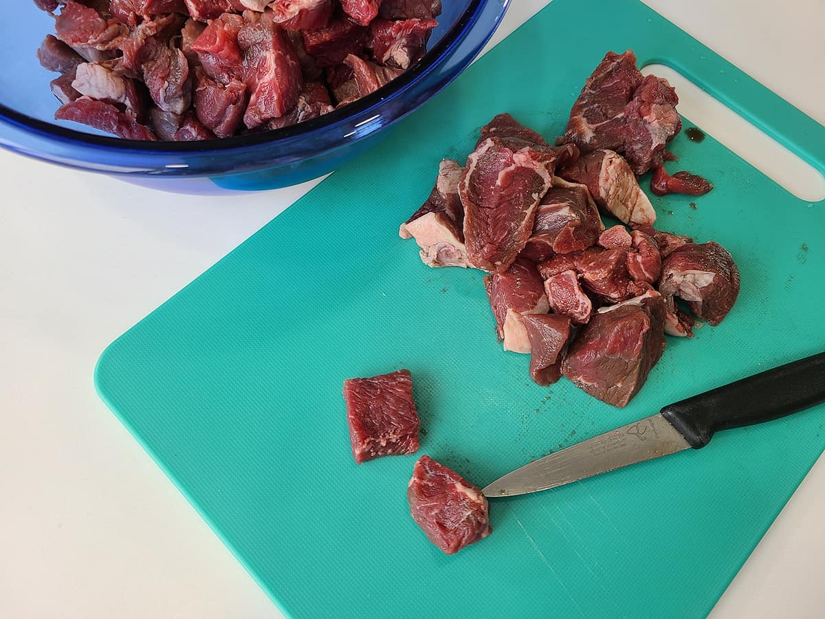 jade colored chopping board with the meat cut into small pieces