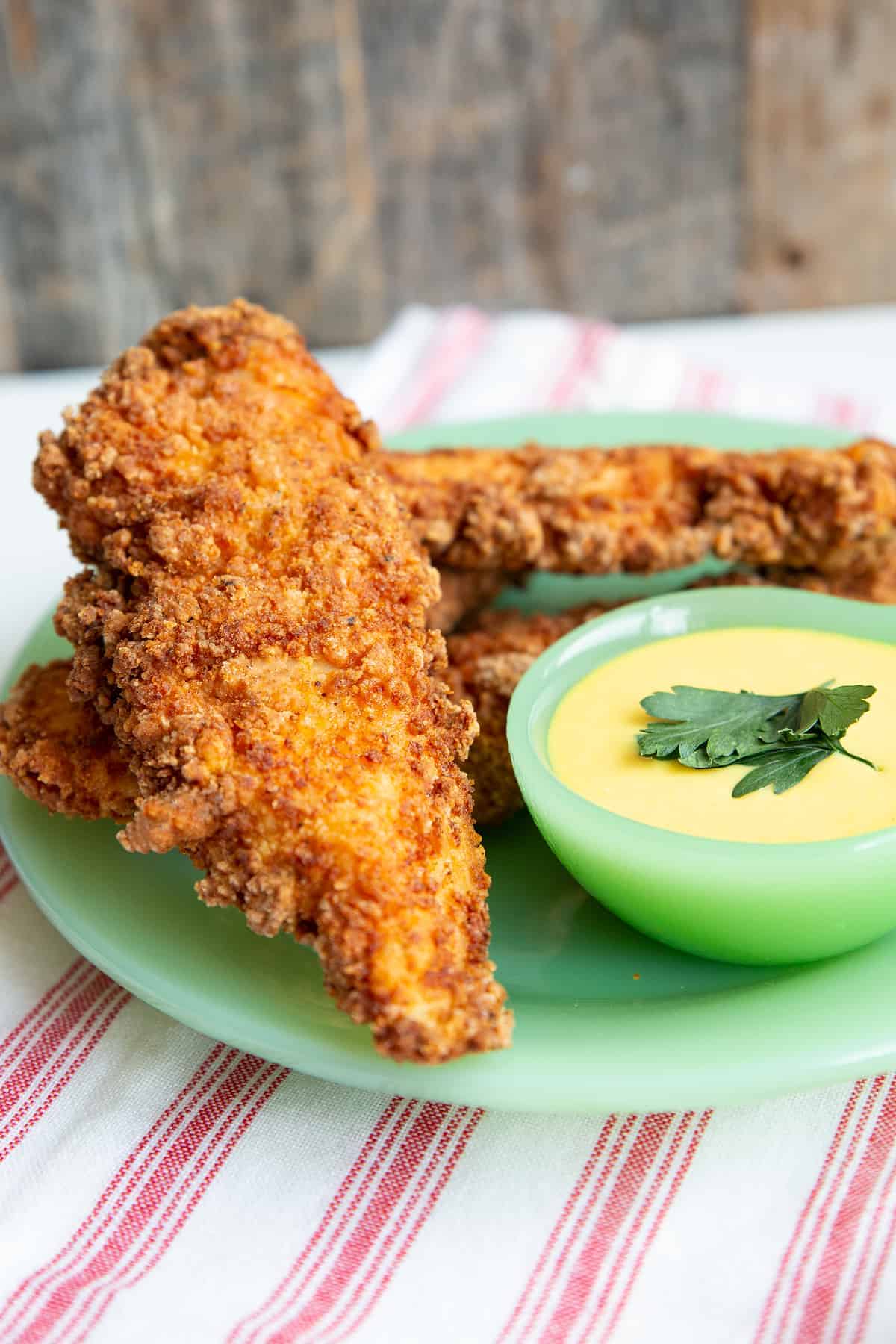 close up Fried Chicken Strips in green jadeite serving dish with the dipping sauce on the side