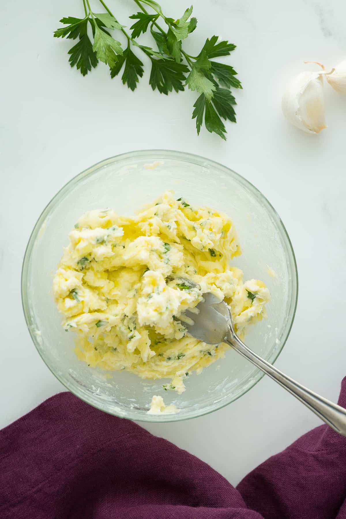 mixed Ingredients for Garlic Butter in a clear bowl with the fork in it