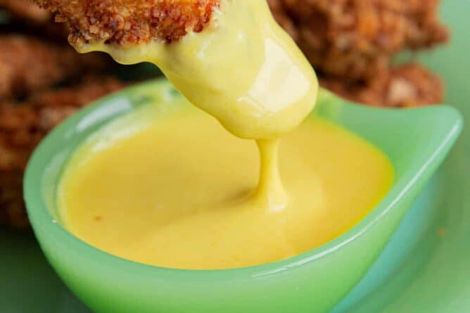 Chicken Strip dipping into a container of honey mustard sauce