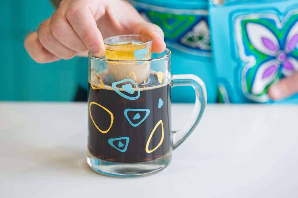 Close up of shot glass filled with irish cream and irish whiskey held over a mug full of beer