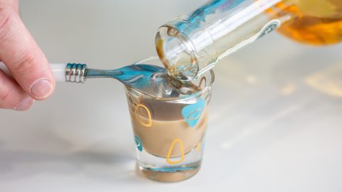 Layering a shot by pouring Irish Whiskey over the back of a spoon into a shot glass ¾ full with irish cream